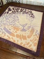 Flat lay of large square scarf showing detailed tiger face design in beige, purple, and orange with dark purple border and Benetton brand text.