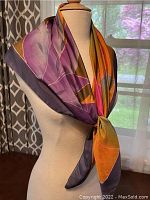 Silk scarf displayed on mannequin showing floral color pattern and hand-rolled edges.
