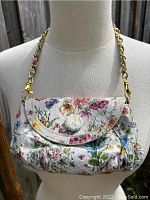Front view of the MARIO V floral snakeskin convertible clutch on a display form showing floral pattern, chain strap, and button closure.
