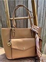 Michael Kors tan leather tote with front pocket and gold hardware, shown with scarf draped over front handle