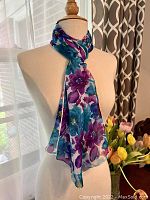 Scarf tied around mannequin neck showing floral pattern and soft drape