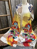 Front view of the scarf draped on a mannequin showing skull, roses, and banners with tattoo art style graphics.