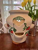 Front view of the terra cotta planter showing the central large pot with three attached smaller strawberry-shaped pots and raised painted strawberry decorations.