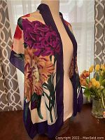 Silk scarf draped on mannequin showing floral design and color contrast with navy border.