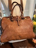 Brown vintage leather handbag showing front with short handles and attached longer cross-body strap