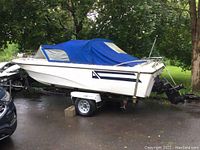 Starboard side view of boat on EZ Load trailer under blue canvas cover