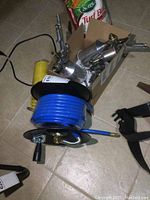 Overview showing black steel hose reel with blue hose and box of spray guns