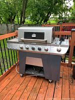 Front view of the Cuisinart gas barbecue grill on a wooden deck with handle, wheels, and control knobs visible.