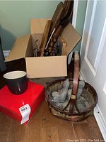 Box with multiple wooden and woven basket items, kitchenware and light items grouped closely, showing breadth of the lot.