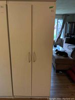 Front view of the white painted pressed wood cabinet showing double doors with curved metal handles.