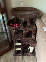 Full front view of the three-level cat tower showing the top perch, hanging basket with blanket, middle platforms, and the bottom area including scratching posts wrapped in sisal.