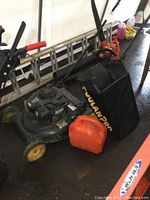 Front-left angle showing mower deck, engine and red fuel can at front