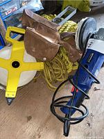 Overview photo showing the polisher, rope, leather pouch, level, and tape measure all together on a surface.