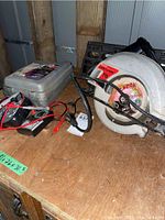 Photo showing Craftsman circular saw, multimeter in case, and jack on wood surface.