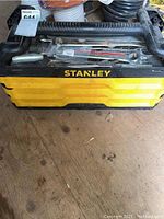 Photo showing top of yellow and black Stanley plastic toolbox with handle and some visible wrench heads inside.