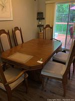 Photo of dining table with six chairs around it showing the table top, chairs, and part of the room.