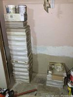 Stack of 15 full boxes plus extra pieces of Naturi ceramic tiles, with buckets of tile adhesive on top.