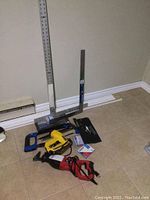 Photo showing the full lot including the sawzall, electric stapler, hacksaw, metal squares, riveting tool and blades on tile floor.