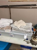 Stack of folded bath towels, face towels, and floor mats in neutral colors placed on a flat surface.