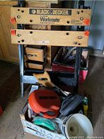 Front full view of Black & Decker Workmate workbench with wooden box containing tools and accessories in front.