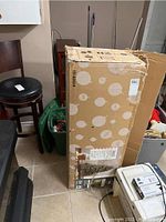 Closed cardboard box with holiday ornament print, showing packaging for 7 foot canvas Christmas tree with lights.