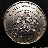 Close-up image of silver coin front with eagle, stars, and text 'ONE TROY OUNCE .999 SILVER LIBERTY SILVER'.