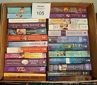 Photo showing box filled with approximately 50 paperback romance novels stacked in two layers.