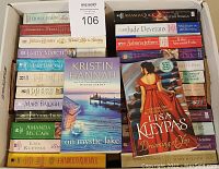Box containing approximately 50 paperback romance books stacked and arranged compactly, showcasing various authors and titles including Kristen Hannah's 'On Mystic Lake' and Lisa Kleypas's 'Dreaming of You'.
