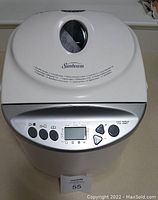 Front top view of Sunbeam breadmaker showing control panel, buttons, and viewing window on top lid.