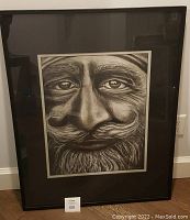 Front view of framed charcoal drawing depicting a bearded man with mustache, under glass.