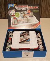 ThinkFun Laser Maze game box open showing maze, laser, targets, and instruction booklet inside.