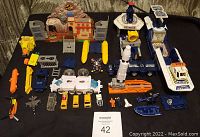 Photo showing all Micromachines items included, featuring several playsets, various vehicles and figures arranged on a black surface with wood panel background.