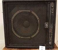 Front view of Peavey TNT wedge bass amplifier showing 15 inch speaker with protective metal grille and control panel on the right side.