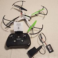 SkyViper drone, black remote controller, battery, and charger shown on flat surface.