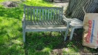 Image of the full wooden outdoor bench placed outside on grass with visible weathering and moss.
