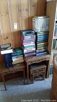 Overall view of carved nesting tables holding four stacks of hardcover books