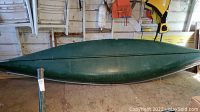 Side profile of green fiberglass canoe showing aluminum gunwale and hull condition