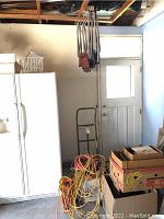 Photo showing hand truck, extension cords on floor, and stacked foldable chairs hanging from ceiling rafters