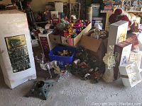 Overall view of Christmas decorations including boxed artificial tree, ornaments, metal reindeer, figurines, wreath, and boxes of china and glassware