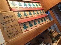Stacked cardboard boxes labeled Fontanini X-Mas creche figures with tree print