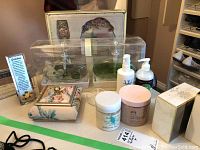 Photo of the collection showing Chanel No 5 perfume box, lotion bottles, body cream jars, glass trinket dish, and decorative floral trinket box