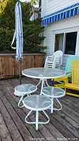Patio set including round glass top table with four attached seats and umbrella