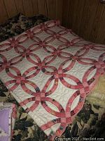 Full view of the quilt laid out showing the patchwork pink and white interlocking circles and squares pattern.