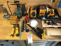 Wide view of various tools, manual sharpeners, a roll of tape, paints brushes, clamps, and other hand tools arranged on a workbench