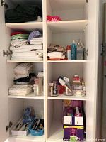 Left cabinet with folded towels, sheets, pillowcases, Poise pads and cosmetics