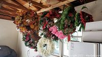 Wreaths hanging in storage area showing various sizes and colors including autumn pumpkin wreath and pink flower wreath