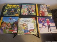 Six children's books displayed on a table: Batman: Toxic Terror, Mulan, Lady and the Tramp, Sofia the First, It’s Earth Day, and Barbie: Ice Skating Dreams.