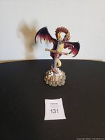 Front view of the dragon statue showing wings, sword, and base with detailed elements.