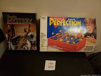 Photo of the closed boxes of Murder Mystery and Perfection vintage games side by side
