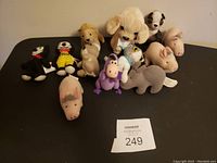 Lot of 11 stuffed animals of various types and colors arranged on a table